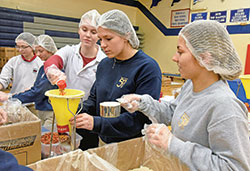 Michelle Belden, left, Kassie Carman, Meg Leising, Chiara Schilten and Peyton Jones, all juniors at Roncalli High School in Indianapolis, assemble meals on March 11 for people in need through an initiative organized by Cross Catholic Outreach. Over the course of the day, Roncalli students assembled 60,000 meals that will be distributed to people in need in such countries as Guatemala, Nicaragua and Haiti. (Photo by Sean Gallagher)