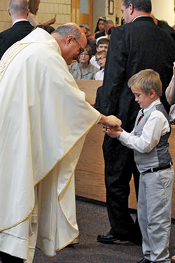 Above, Patrick Evans, a member of St. Susanna Parish in Plainfield, recieves his first Communion from Msgr. William F. Stumpf, vicar general, during a Mass at the parish church on May 4, 2019. (File photo by Sean Gallagher)