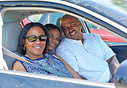 Gretchen, left, Austin and Reggie Horne, members of Holy Angels Parish in Indianapolis, smile in their car after worshiping at an outdoor Mass celebrated by Archbishop Charles C.  Thompson at the parish school’s parking lot on June 7. Worshipers remained in their cars during the Mass to observe COVID-19 safety guidelines. (Photo by Natalie Hoefer)