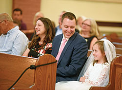 Ashley and Andrew Wells share a light moment with their daughter Olivia during a June 13 Mass at Our Lady of the Most Holy Rosary Church in Indianapolis at which Olivia received her first Communion. (Photo by Sean Gallagher)
