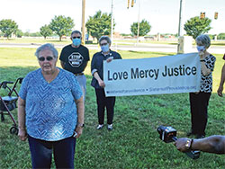 Providence Associate Priscilla Hutton speaks during a press conference on the morning of July 13 outside the Federal Correctional Complex in Terre Haute. Behind her, Providence Sister Paula Damiano holds a banner. (Photo by Natalie Hoefer)