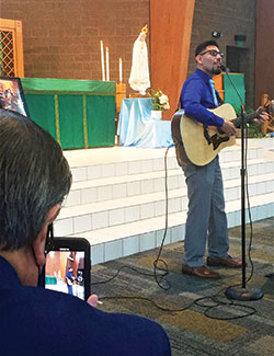 Carlos Ramirez, left, records a video of his son, Carlos Roberto Ramirez of Laredo, Texas, right, as Roberto sings a song during the archdiocesan “Morning with Mary” event at St. Jude Church in Indianapolis on Oct. 10. (Photo by Natalie Hoefer)