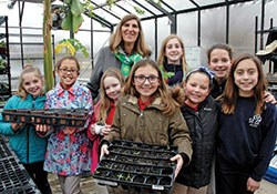 Members of the horticulture club at St. Bartholomew School in Columbus pose for a photo with principal Helen Heckman in the school’s greenhouse-outdoor learning lab in March. (File photo by John Shaughnessy)