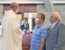 Bryan Stater, center, prepares to receive the sacrament of confirmation from Father Christopher Wadelton on June 14 at St. Bartholomew Church in Columbus. His sponsor, Deacon William Jones, stands by at right. (Submitted photo)