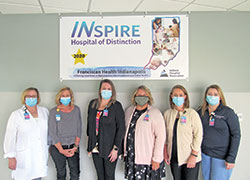 Angela Bratina, third from right, administrative director of Franciscan Health Indianapolis’ Center for Women & Children, poses with nurses Christine Hunkele, left, Erin Neu, Melanie Boosey, Jennifer Naessens and Stephanie Lee in front of a banner noting the recognition they helped earn for Franciscan Health from the Indiana Hospital Association as an INspire Hospital of Distinction in the area of care for mothers and babies. (Submitted photo)