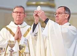 Lafayette Bishop Timothy L. Doherty, left, concelebrates as Archbishop Charles C. Thompson raises the Blessed Sacrament during a Jan. 22, 2020, Mass at St. John the Evangelist Church in Indianapolis prior to the Indiana March for Life. (Criterion file photo by Sean Gallagher)
