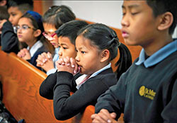Ruth San, second from right, kneels in prayer during a Feb. 2, 2020, Mass at St. Mark the Evangelist Church in Indianapolis. She is one of more than 250 Burmese students enrolled in the school of the Indianapolis South Deanery faith community. (Submitted photo by Steve Raymer)
