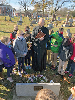 Father Michael Keucher led the fourth- and fifth-grade students of St. Joseph School in Shelbyville on an All Souls Day visit to St. Vincent Cemetery in Shelby County and St. Joseph Cemetery in Shelbyvile. Father Keucher led a prayer service at each cemetery where students performed the spiritual work of mercy of praying for the dead. Many students knew where some of their relatives are buried so their pastor blessed those graves. (Submitted photo)