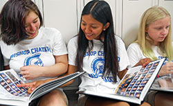 Bishop Chatard High School student Deysi Garcia-Vazquez, center, enjoys checking out the Indianapolis North Deanery high school’s new yearbook at the beginning of the 2019-20 academic year with fellow Trojans Emma Shea, left, and Gracie Dillon. (Submitted photo)