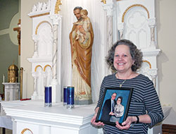 The feast day of St. Joseph holds a special place in the family of Francis and Jody Hammans. Here, their daughter, Lori Hammans Tobin, holds a photo of the couple as she stands near a statue of St. Joseph in St. Joseph Church in Indianapolis. (Photo by John Shaughnessy)