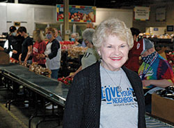 Throughout the pandemic, Darlene Sweeney has felt her prayers have been answered in her role as director of volunteer services for the Indianapolis Council of the Society of St. Vincent de Paul. In this March 24 photo, she poses at the society’s food pantry in Indianapolis as volunteers from St. Mark the Evangelist Parish in Indianapolis put together boxes of food for home deliveries to people in need. (Photo by John Shaughnessy) 