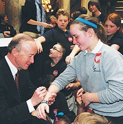 Then-Gov. Mitch Daniels signs Celia Ward’s arm following the school choice bill signing ceremony on May 5, 2011. At the time, Celia was a fourth-grade student at Central Catholic School in Indianapolis, one of four schools which now make up the Notre Dame ACE Academies in Indianapolis. (Criterion file photo courtesy of the Governor’s Office)