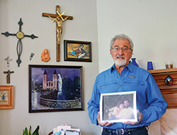 Standing in the area of his home where he prays, Richard Turi holds a photo of him and his wife Gail before they married. The couple, members of St. Thomas Aquinas Parish in Indianapolis, were devoted to praying the rosary daily. He continues the practice as a widower. (Photo by Natalie Hoefer)