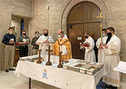 With seminarians gathered around him, Benedictine Father Justin DuVall, center, blesses candles on Feb. 2 at Bishop Simon Bruté College Seminary in Indianapolis. The archdiocesan-operated college seminary experienced challenges during the past year as it sought to form men for the priesthood during the coronavirus pandemic. (Submitted photo)