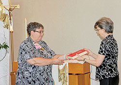 Benedictine Sister Julie Sewell ritually receives a copy of the Rule of St. Benedict from Benedictine Sister Jeanne Weber during a June 5 Mass at the chapel of Our Lady of Grace Monastery in Beech Grove in which Sister Julie was installed as the ninth prioress of the monastic community. Sister Jeanne is president of the Federation of St. Gertrude, an organization of 12 women’s Benedictine communities in Canada and the United States. (Photo courtesy of Our Lady of Grace Monastery)