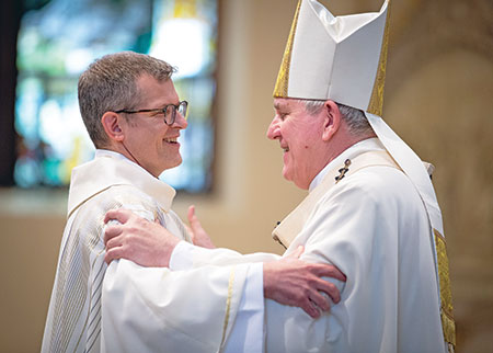Jesuit Father Jeffrey Sullivan exchanges a sign of peace with Milwaukee Archbishop Jerome E. Listecki during a June 12 Mass at the Church of the Gesu in Milwaukee during which he was ordained a priest for the Society of Jesus’ Midwest Province. Father Sullivan grew up as a member of Holy Name of Jesus Parish in Beech Grove. (Submitted photo by Jeff Zmania)