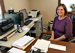 Janet Peter, secretary for the parishes of Holy Cross in St. Croix, St. Augustine in Leopold and St. Mark in Perry County, sits at her desk at St. Mark Parish. (Submitted photo)