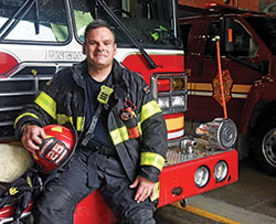 Indianapolis Fire Department firefighter Thomas McKiernan sits on Aug. 25 on the bumper of a fire engine in Station 25 in Indianapolis. McKiernan was on his second day on the job as a firefighter on Sept. 11, 2001. (Photo by Sean Gallagher)