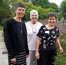 Sister Marie Therese Racine, left, Sister Angela Jarboe and Sister Sheila Marie Fitzpatrick, all members of the Benedictine Our Lady of Grace Monastery in Beech Grove, pose on Oct. 4 in their community’s Peace and Nature Garden. (Photo by Sean Gallagher)