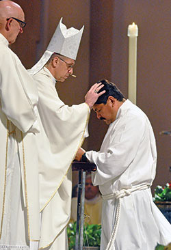 Then-Archbishop-designate Charles C. Thompson ritually lays hands on deacon candidate Juan Carlos Ramirez on June 24, 2017, in SS. Peter and Paul Cathedral in Indianapolis during a Mass in which Ramirez and 20 other men from across central and southern Indiana were ordained as permanent deacons. (File photo by Sean Gallagher)
