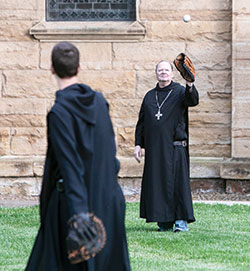 Benedictine Archabbot Kurt Stasiak plays catch on May 22, 2020, on the lawn by Saint Meinrad Archabbey and its Church of Our Lady of Einsiedeln in St. Meinrad. Times of recreation can help Benedictines enter more deeply into the work and prayer that is at the heart of their vocation. (Photo courtesy of Saint Meinrad Archabbey)