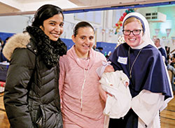 Sister of Life Lucia Christi smiles while holding a newborn during a Christmas party while serving a two-year mission at the Sisters of Life’s crisis pregnancy center in New York City, where they provide support to pregnant women in crisis and offer continuing support to them following the birth of their children. (Submitted photo courtesy of the Sisters of Life)