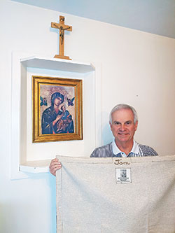 Tom Yost shows the blanket, a gift from his parish, that gave him a sense of comfort and support during his treatments for cancer. (Submitted photo)