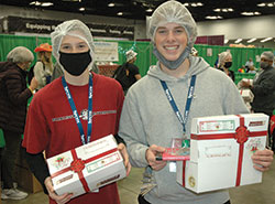 Charlotte Wiman, left, and Aidan Sauls of Our Lady of the Hills Parish in Columbia, S.C., are all smiles as they help with the Box of Joy service project at the National Catholic Youth Conference in Indianapolis on Nov. 19. (Photo by John Shaughnessy)