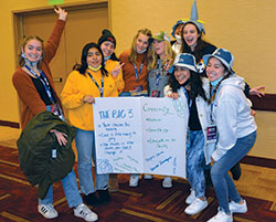 Abilene, Texas, residents Adeline Fellona, left, and her sisters Tessa and Margaux, fourth and fifth from left, of the Archdiocese of the Military Services, pose on Nov. 19 with the poster they and members of the archdioceses of Atlanta, Chicago and Indianapolis made of their take-aways from NCYC in Indianapolis and how they can put them into action. (Photo by Natalie Hoefer)