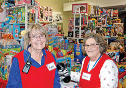 Sharing smiles and gifts, Patti Jensen and Helen Burke are among the Red Aprons core group of volunteers at the Christmas Store, the annual effort by Catholic Charities Indianapolis to make the holy day extra special for families in need. (Photo by John Shaughnessy)