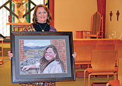 In the adoration chapel of her parish, St. Alphonsus Liguori in Zionsville, Ind. (Lafayette Diocese), where she prays daily, D. Anne Jones holds a portrait she painted through her organization, Face to Face Fine Art, of Deb Perry, the late wife of Deacon Tim Perry, who ministers at the parish. (Photo by Natalie Hoefer)