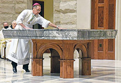 Archbishop Charles C. Thompson spreads chrism oil on the altar of St. John Paul II Church in Sellersburg during a Dec. 19, 2021, dedication Mass for the new church of the New Albany Deanery faith community. (Photo by Sean Gallagher)