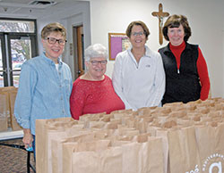 JoAn Reed, left, Theresa Desautels, Terry Buckman and Patty Schipp work together as part of the Weekend Meals program that provides bags of take-home food for children at five Catholic schools in Indianapolis. (Photo by John Shaughnessy)
