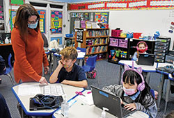 Pam Wells, principal of St. Mary School in Rushville, assists second grader Corbin Snow, center, on Jan. 7 at the Connersville Deanery school. Second grader Chloe Ni works on a computer at right. (Photo by Sean Gallagher)