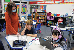 Pam Wells, principal of St. Mary School in Rushville, assists second grader Corbin Snow, center, on Jan. 7 at the Connersville Deanery school. Second grader Chloe Ni works on a computer at right. (Photo by Sean Gallagher)