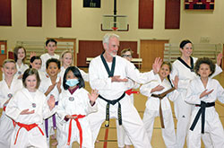 Students of St. Barnabas School in Indianapolis follow the lead of their pastor, Father Guy Roberts, in doing a tae kwon do move during an after-school class. Thirty-five students train twice a week with Father Roberts, who has a black belt in tae kwon do. (Photo by John Shaughnessy)