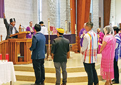 Paul Hnin of St. Barnabas Parish invites the congregation to respond to a petition during a Mass for peace in Myanmar celebrated at St. Mark the Evangelist Church in Indianapolis on March 20. Archbishop Charles C. Thompson, to the right of Hnin, served as principal celebrant. (Photo by Natalie Hoefer)