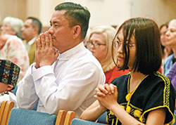 Stephen Aye, left, and Theresa Soe kneel in prayer at the archdiocesan chrism Mass. Both emigrated to Indianapolis from Myanmar and are part of a large community of Burmese Catholics at St. Mark the Evangelist Parish in Indianapolis. (Photo by Sean Gallagher)