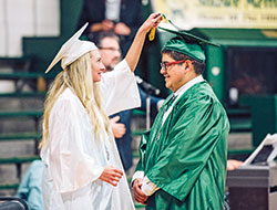 During the graduation ceremony of Father Michael Shawe Memorial High School in Madison in 2021, Lillian Heath turns the tassels from one side to the other on the graduation cap of fellow senior Leonel Rios-Amaro—displaying a longstanding tradition among seniors at Shawe to show that they have now graduated. (Photo courtesy of Laura Jayne Gardner Photography)