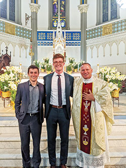 Standing between his sponsor Stone Robbins, left, and his pastor Father Rick Nagel of St. John the Evangelist Parish in Indianapolis, right, Adam Scott smiles with joy after the Easter Vigil Mass at St. John the Evangelist Church on April 16, when he joined the full communion of the Church. (Submitted photo)