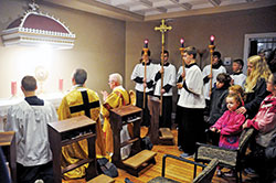 Father Jonathan Meyer, co-pastor of All Saints Parish in Dearborn County, second from left, and Deacon Robert Decker join several altar servers and other parishioners in praying before the Blessed Sacrament on March 1, 2017, the day on which the Batesville Deanery faith community’s perpetual adoration chapel on its St. John the Baptist campus in Dover was inaugurated. (File photo by Sean Gallagher)
