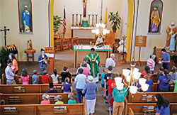 A visiting priest distributes Communion during Mass in St. Mark Church in Perry County during Totus Tuus in 2018. (Submitted photo)