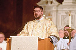 Transitional Deacon Michael Clawson proclaims the Gospel on April 12 at SS. Peter and Paul Cathedral during the annual archdiocesan chrism Mass. (Photo by Sean Gallagher)