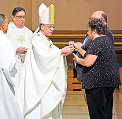 Archbishop Charles C. Thompson receives the gifts from Joy and Steve Day, members of Holy Spirit Parish in Indianapolis, during a Mass for members of the United Catholic Appeal’s Miter Society and the archdiocesan Catholic Community Foundation’s Legacy Society at SS. Peter and Paul Cathedral in Indianapolis on May 12. (Photo by Natalie Hoefer)