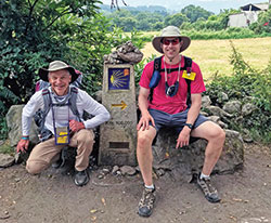 Dr. David Weigel, left, and his son Dr. Eric Weigel, members of St. Mary Parish in Greensburg, pose on July 20, 2021, by a milestone on the Camino pilgrimage path in Spain. They joined men from across the archdiocese in journeying to the historic shrine of St. James in Santiago de Compostela. (Submitted photo)