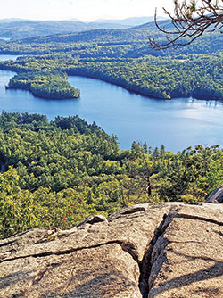 From atop West Rattlesnake Mountain in Holderness, N.H., Squam Lake glistens while the White Mountains fade into the distance. (Photo by Natalie Hoefer)