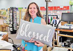 Store owner Tina Sherman holds a pillow  with the word “Blessed” in The Ark Book and Gift Store in Columbus. (Photo by Jennifer Lindberg)