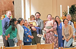 Dr. Michael Padilla, center, smiles with his family in SS. Peter and Paul Cathedral in Indianapolis after receiving the archdiocese’s Archbishop O’Meara Respect Life Award during the Respect Life Mass on Oct. 2. Among those posing with him are his wife Dana (holding their son Gabe) their daughter Mary Elise (holding the award) and his parents Lourdes and Mike Padilla, third from right and far right, respectively. (Photo by Natalie Hoefer)