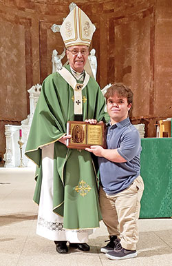 Eric Dessauer smiles as he receives the archdiocese’s Our Lady of Guadalupe Pro-Life Youth Award presented to him by Archbishop Charles C. Thompson during the Respect Life Sunday Mass in SS. Peter and Paul Cathedral in Indianapolis on Oct. 2. (Photo by Natalie Hoefer)