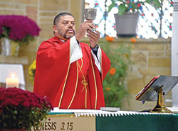 Father Juan Valdes, pastor of St. Anthony Parish in Indianapolis, elevates a chalice on Oct. 19 during a Mass in his parish’s church. (Photo by Sean Gallagher)